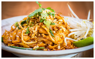 Thai noodles with crushed peanuts, sauce, line, and bean sprouts.