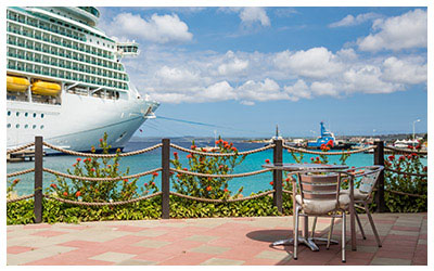 Image of a table and chairs at port looking at a cruise ship.