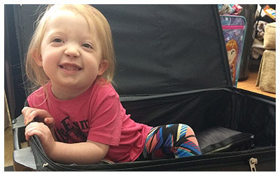 Image of a little girl playing in a suitcase.