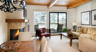 Photo of hotel room living space with fireplace, couch and balcony.