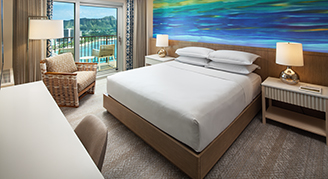 Image of a bed leading to a balcony in a Deluxe Oceanfront Room.
