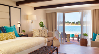 Image shows featuring a king-sized bed, exposed ceiling beams, and a sliding glass door opening to an outdoor patio area