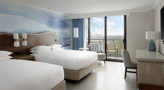 A room featuring two double beds and a balcony.