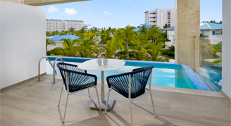 Photo of hotel room balcony with two chairs, a small table and pool.
