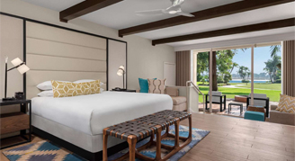 Image shows featuring a king-sized bed, exposed ceiling beams, and a sliding glass door opening to an outdoor patio area