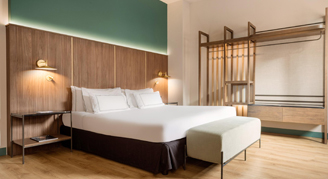 A room with one bed, a bench and a wardrobe area.