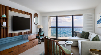 Living room seating area with sliding glass doors leading out to an ocean view.