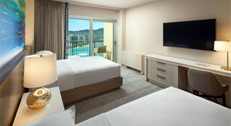 Image of a two beds leading to a balcony in a Deluxe Oceanfront Room.