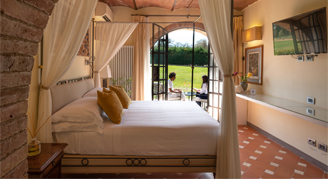 Image of a single bed in a Deluxe Room with Terrace leading to an opened door.