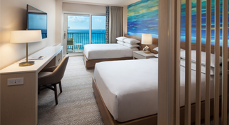 Image of two beds and a work area leading to a balcony in a High-Floor Oceanfront Room.