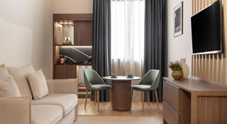 A seating area, dining area and television with a window in the background.