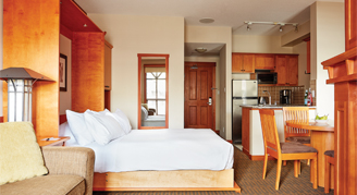 Hotel room with bed, dining table, and kitchen.