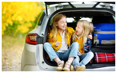 Two children sitting in the back of an open car