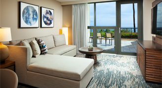 Image of a sofa and balcony overlooking the ocean and surrounding area.