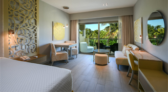 Photo of hotel room with bed, living space and balcony with a garden view.