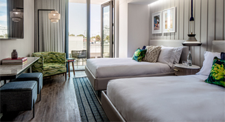 Image of two beds with floor-to-ceiling windows in a Deluxe Room.