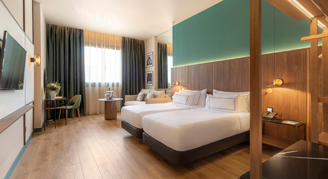 Two beds, a seating area and television with a window in the background.