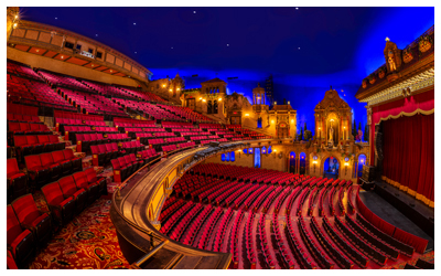 An empty theater with traditional red velvet seats and decorative wood paneling.