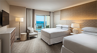 Imgae shows two beds and a view of the ocean.