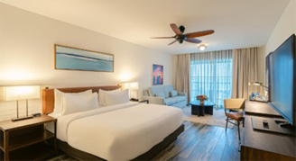 Image of a single bed, television and couch leading to a balcony in a River-View Room.