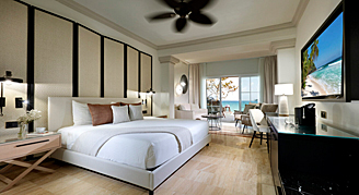 Junior Suite featuring a king-size bed and a private balcony overlooking the ocean.
