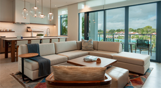 The image shows a family area with a kitchen and dining area in the background and a view outside.