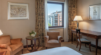 Image of a bed and a window overlooking the city in a Classic Room.