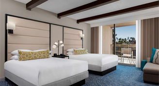 Image shows a two-queen beds with exposed ceiling beams and patio in the background.