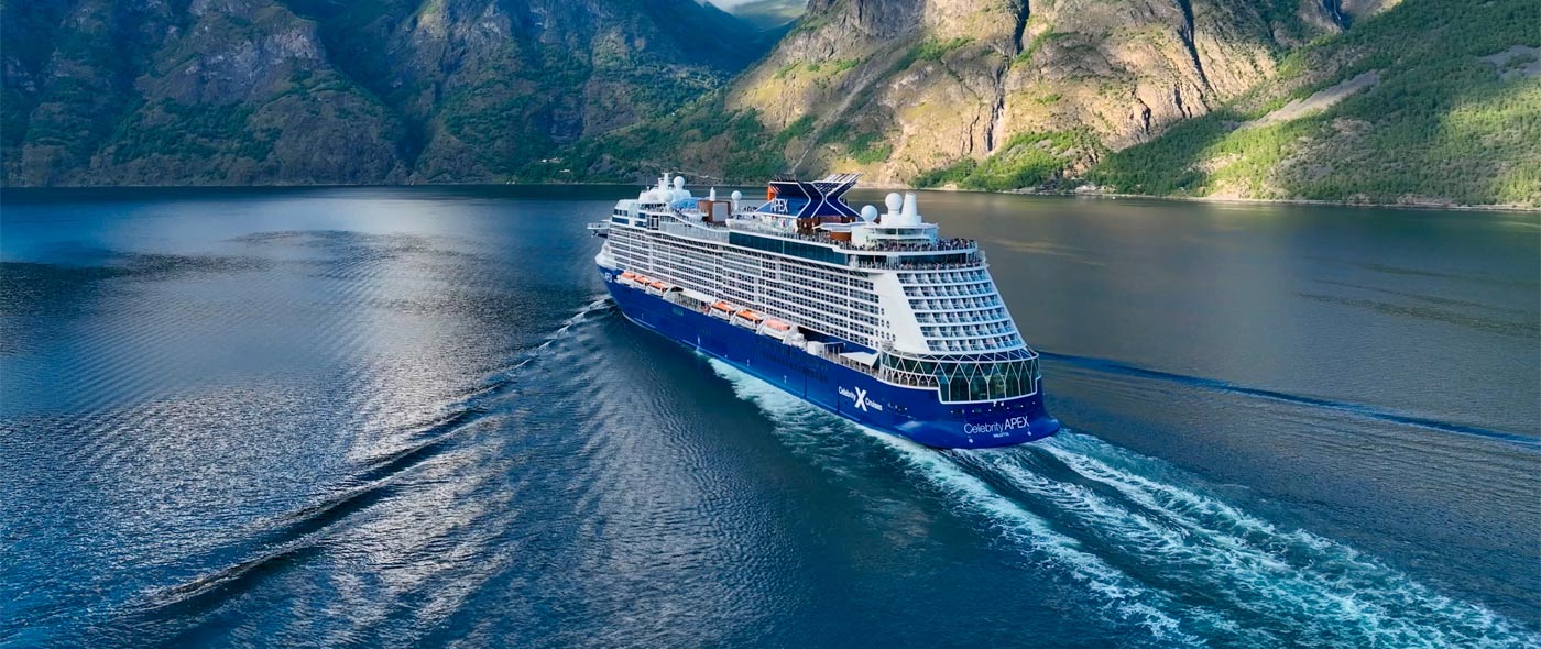 Photo of Celebrity ship sailing by large mountains.