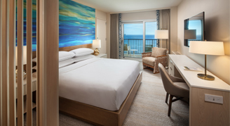 Image of a bed and a work area leading to a balcony in a High-Floor Oceanfront Room.