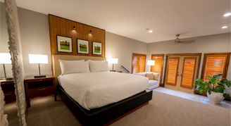 Bright modern hotel bedroom featuring a king-sized bed with crisp white linens, light wood paneling.