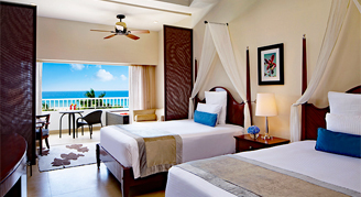 Two double beds with a balcony view of the ocean.