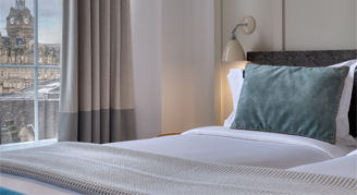 Image of a single bed in a City-View One-Bedroom Suite with adjacent window.