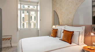 Image shows a plush king bed with burnt-orange accent pillows.