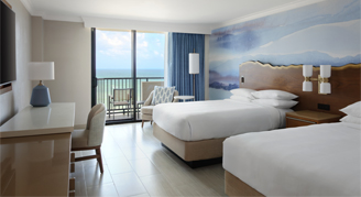 An oceanfront front room featuring two double beds and a balcony.