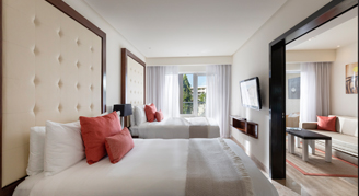 A view of a two room unit with two beds, a seating area and views of the gardens.