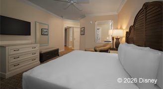 Hearing accessible one-bedroom with a a king bed with a decorative wooden headboard.