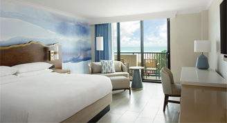 A room featuring a king bed and a balcony with a partial-ocean-view.
