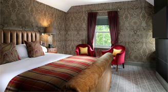 Image shows a king bed wth red stripped cover blanket and a view out the window.