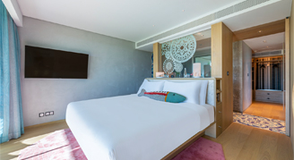 The image shows a platform bed with plush fish pillow and tv mounted.