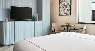 Photo of hotel room with TV and small table with chairs.