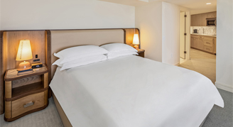 View of king bed with bed table and lamp.