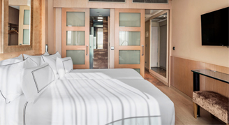 Image of a two beds side-by-side and nearby doorway in a Melia Room.