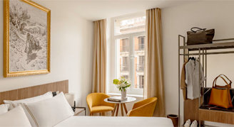 Photo of hotel room with bed and a small window and sitting area.