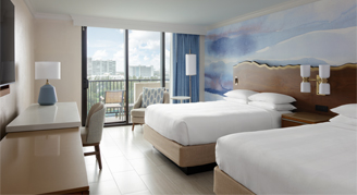 A room featuring two double beds and a balcony with a partial-ocean-view.