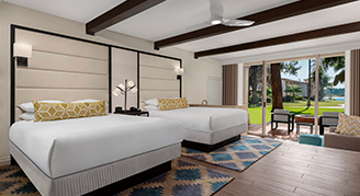 Image shows featuring two Queen-sized beds, exposed ceiling beams, and a sliding glass door opening to an outdoor patio area