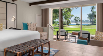 Image shows featuring a Queen-sized bed, exposed ceiling beams, and a sliding glass door opening to an outdoor patio area