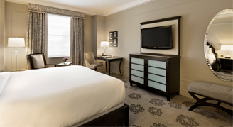 Image of Fairmont Deluxe room with a queen bed and modern dark wood dresser.
