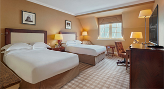 Image of the Fairmont Room with two beds, work desk and adjacent window.