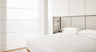 Image of a single bed next to a window in a Corner River-View Room.